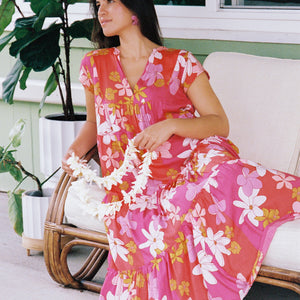 woman with brown hair wearing a pink short sleeve tiered maxi dress with retro flower print