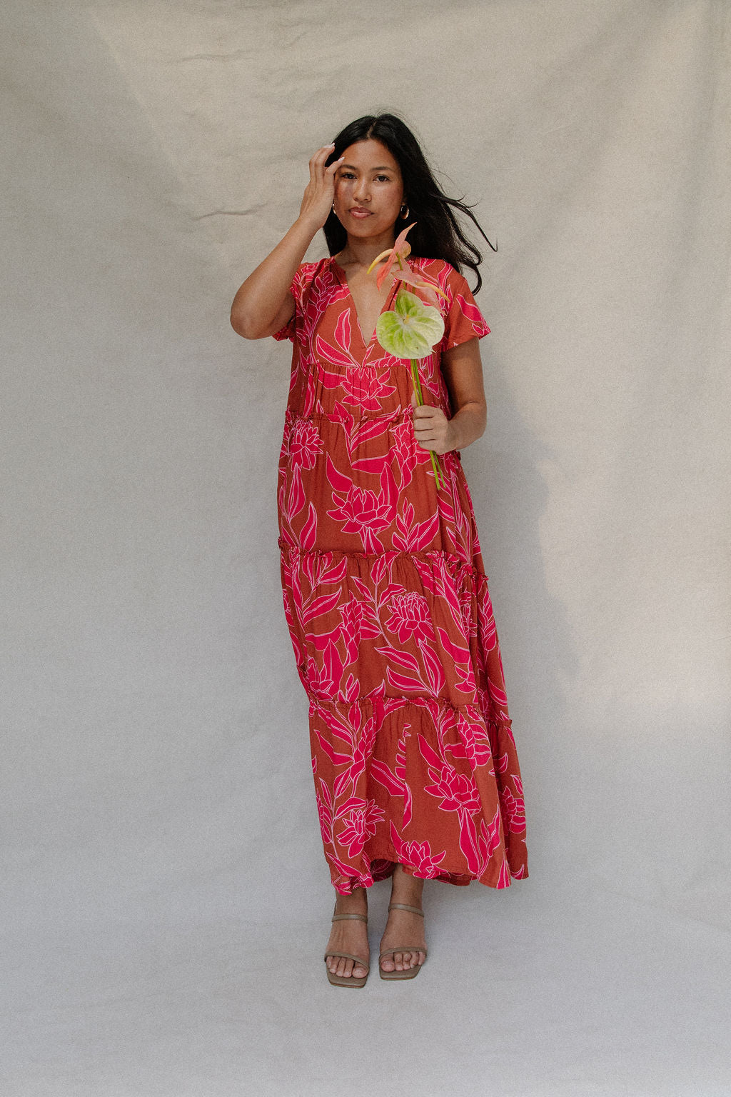 woman with brown hair wearing a sienna colored maxi v neck dress with awapuhi pattern