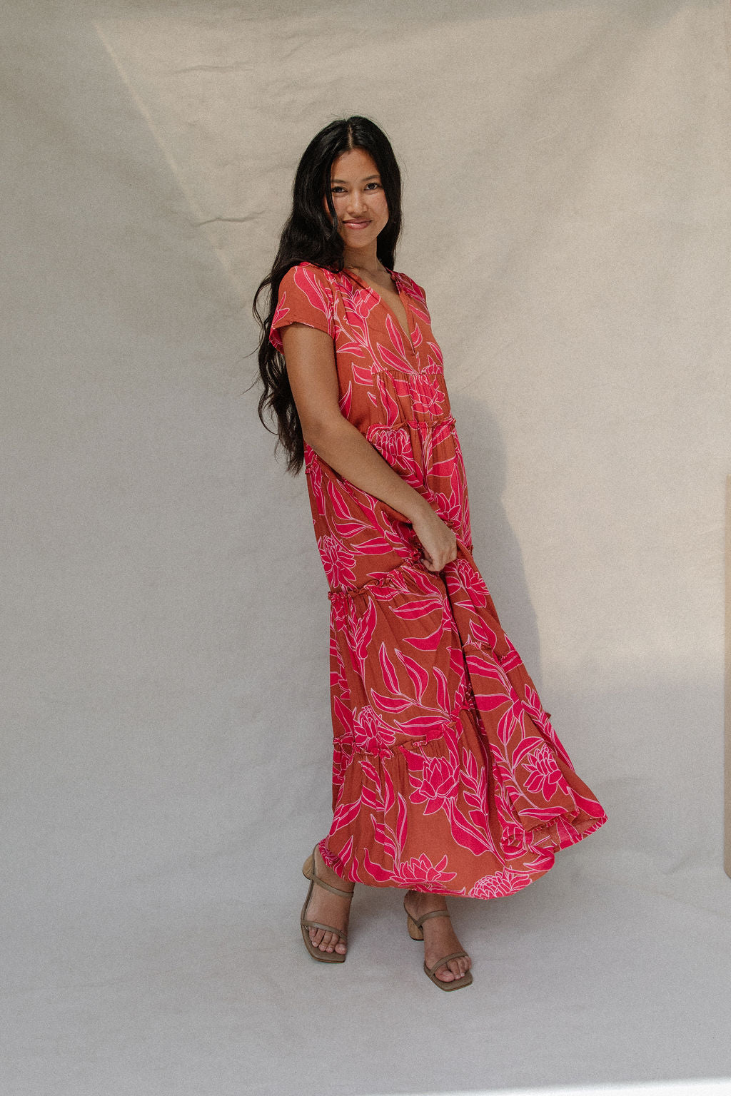 woman with brown hair wearing a sienna colored maxi v neck dress with awapuhi pattern