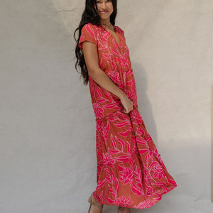woman with brown hair wearing a sienna colored maxi v neck dress with awapuhi pattern