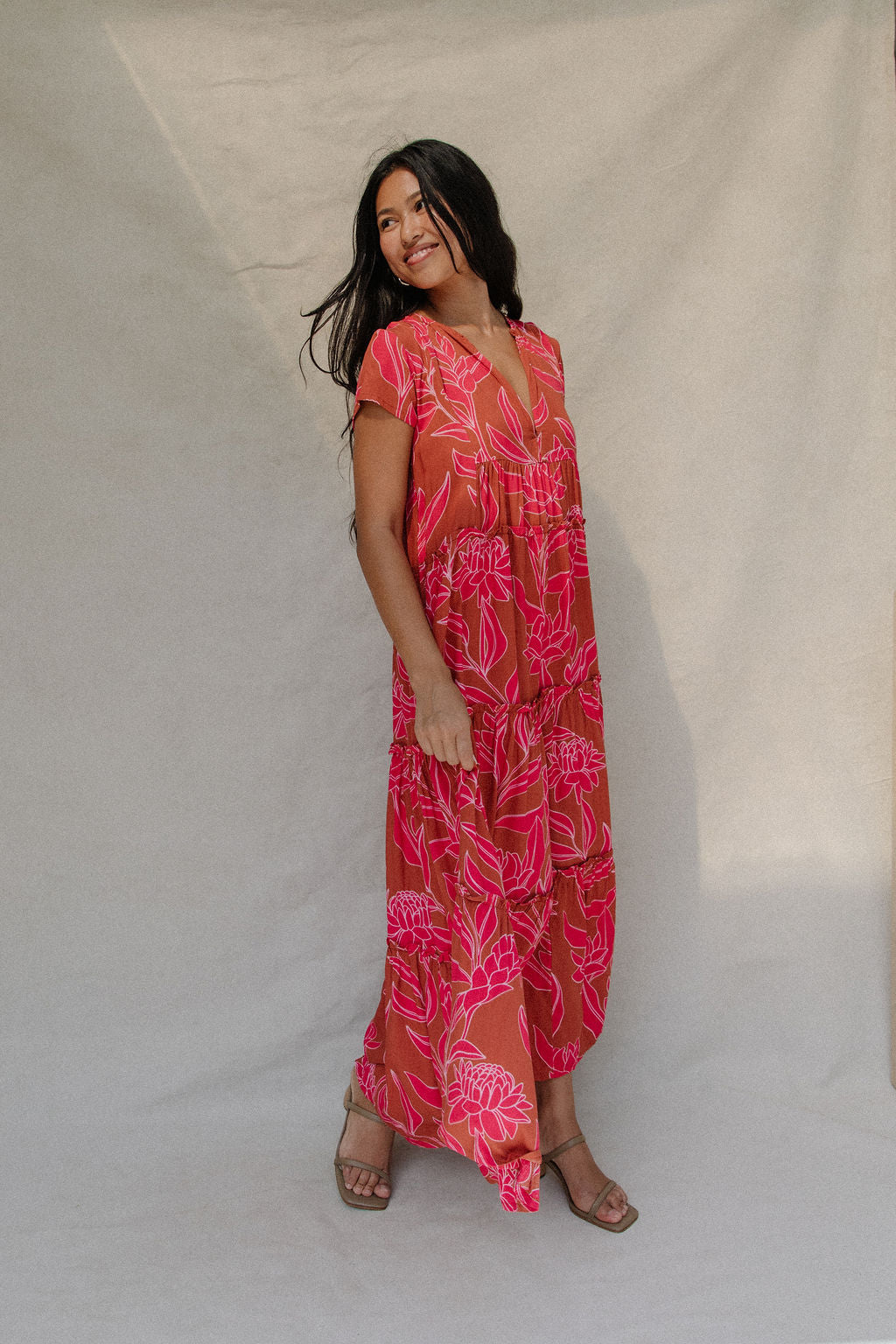 woman with brown hair wearing a sienna colored maxi v neck dress with awapuhi pattern