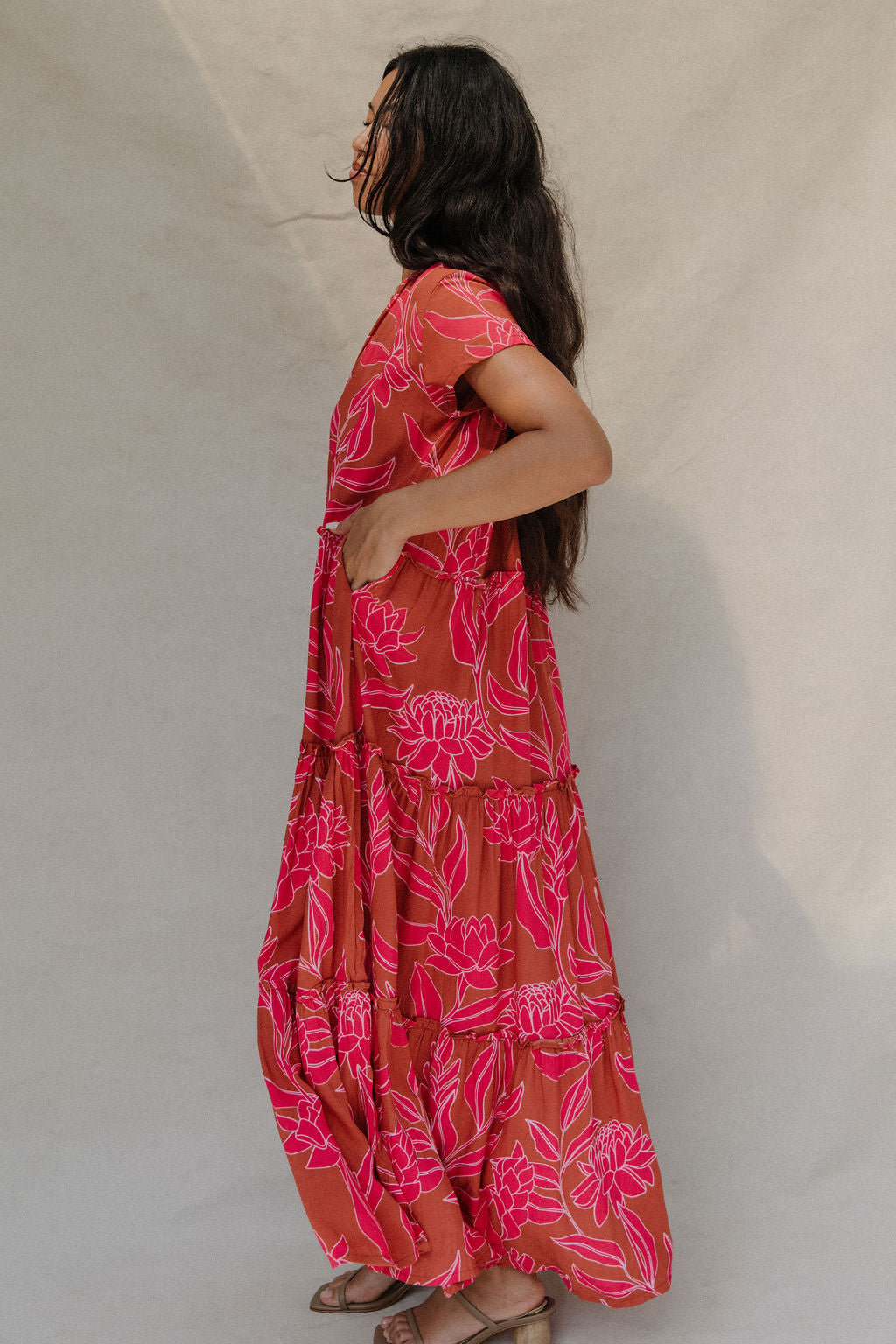 woman with brown hair wearing a sienna colored maxi v neck dress with awapuhi pattern