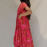 woman with brown hair wearing a sienna colored maxi v neck dress with awapuhi pattern