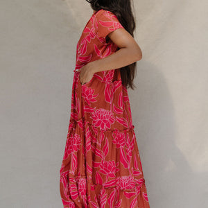 woman with brown hair wearing a sienna colored maxi v neck dress with awapuhi pattern