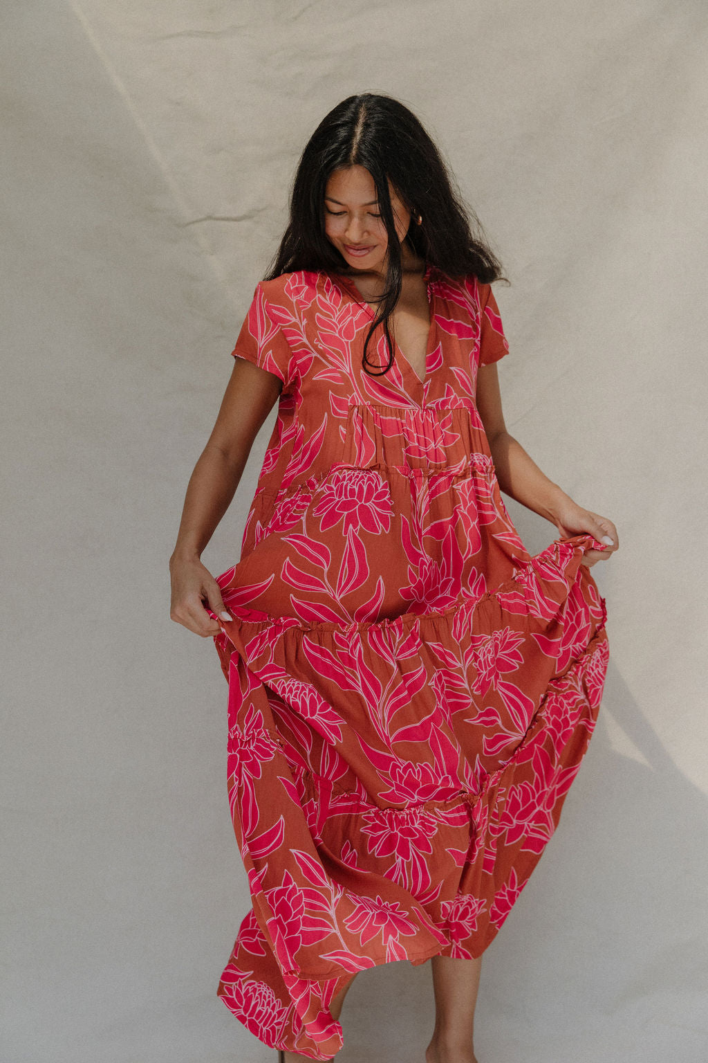 woman with brown hair wearing a sienna colored maxi v neck dress with awapuhi pattern