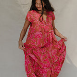 woman with brown hair wearing a sienna colored maxi v neck dress with awapuhi pattern