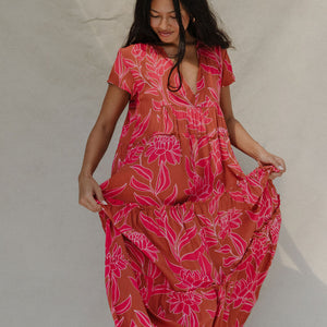 woman with brown hair wearing a sienna colored maxi v neck dress with awapuhi pattern