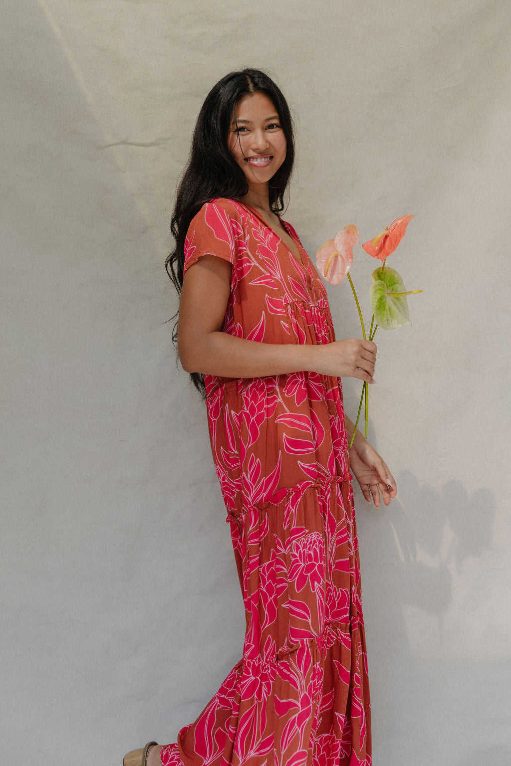 woman with brown hair wearing a sienna colored maxi v neck dress with awapuhi pattern