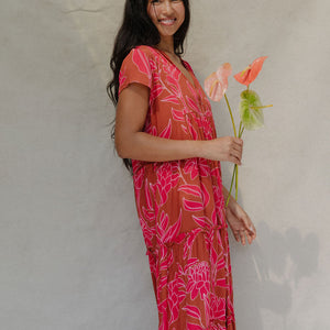 woman with brown hair wearing a sienna colored maxi v neck dress with awapuhi pattern