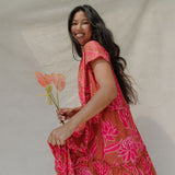 woman with brown hair wearing a sienna colored maxi v neck dress with awapuhi pattern