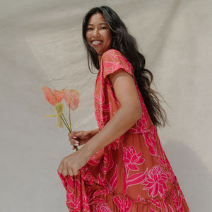 woman with brown hair wearing a sienna colored maxi v neck dress with awapuhi pattern