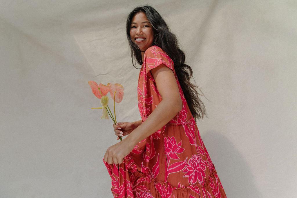 woman with brown hair wearing a sienna colored maxi v neck dress with awapuhi pattern