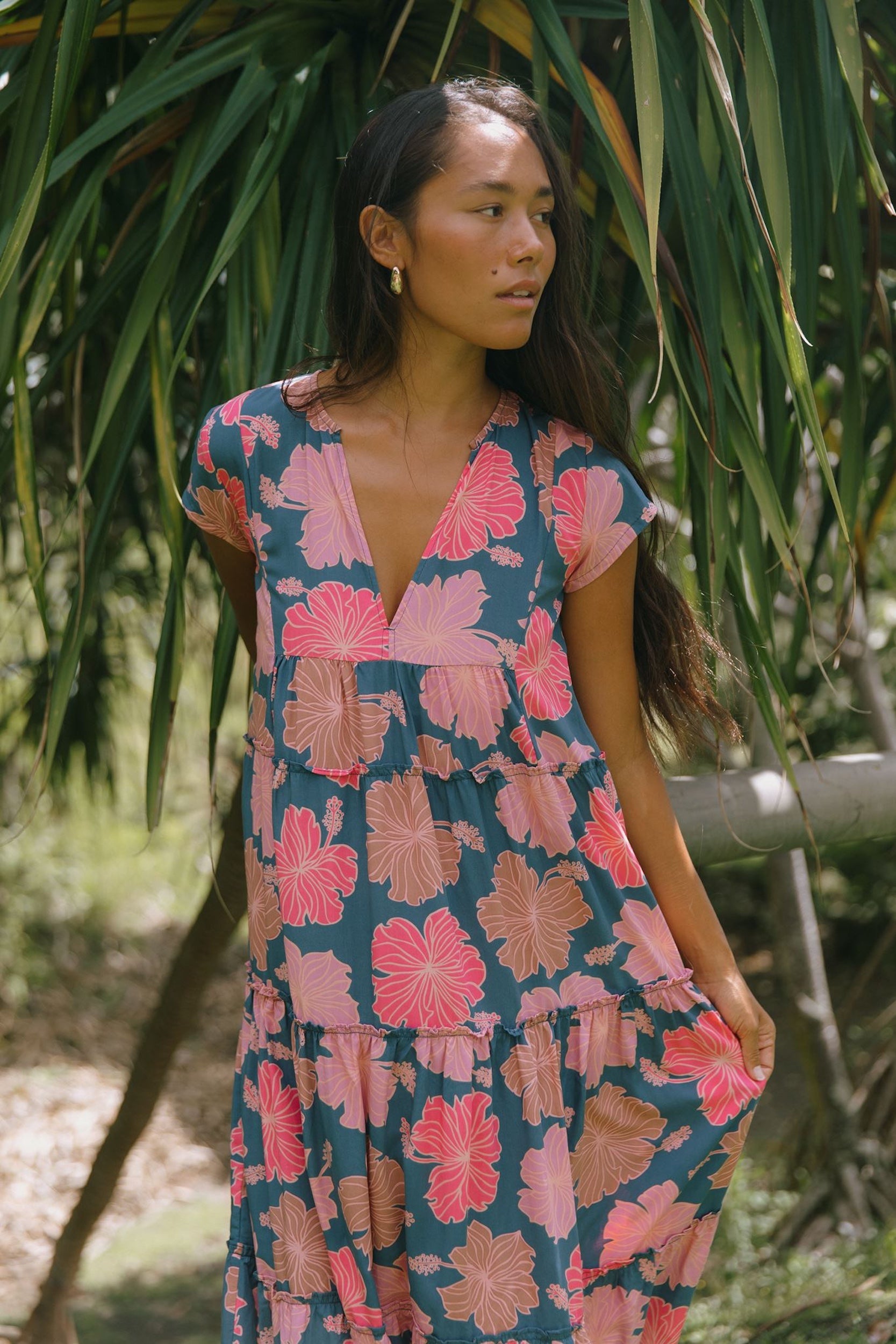 woman with brown hair wearing a navy maxi dress with bright pink hibiscus