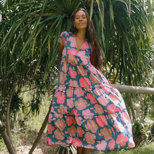 woman with brown hair wearing a navy maxi dress with bright pink hibiscus