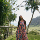 woman with brown hair wearing a navy maxi dress with bright pink hibiscus