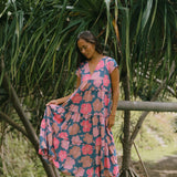 woman with brown hair wearing a navy maxi dress with bright pink hibiscus