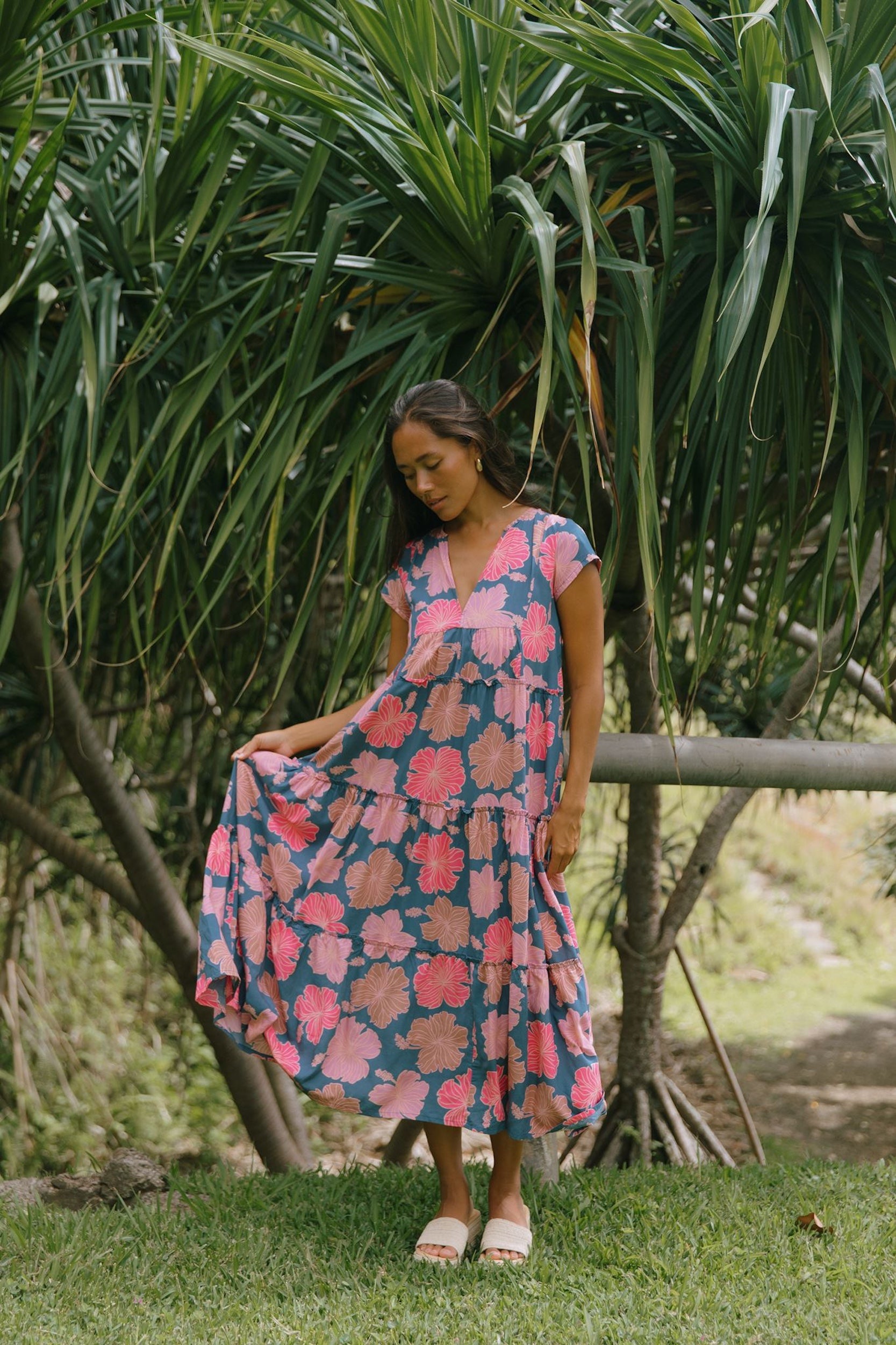 woman with brown hair wearing a navy maxi dress with bright pink hibiscus