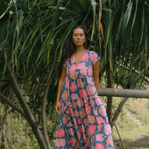 woman with brown hair wearing a navy maxi dress with bright pink hibiscus