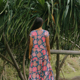woman with brown hair wearing a navy maxi dress with bright pink hibiscus