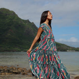woman with brown hair wearing long tiered maxi dress in dark teal with shell lei print