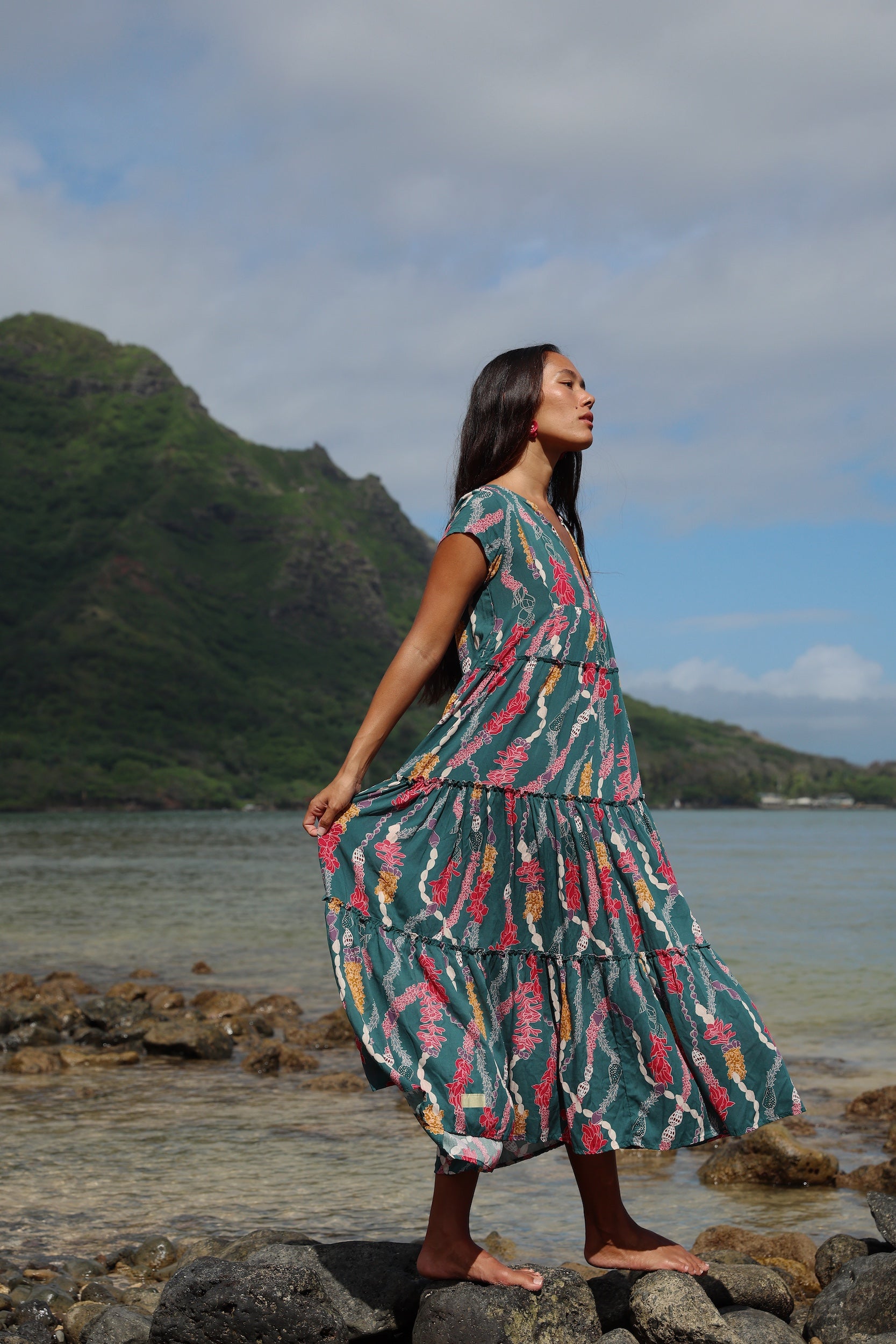 woman with brown hair wearing long tiered maxi dress in dark teal with shell lei print