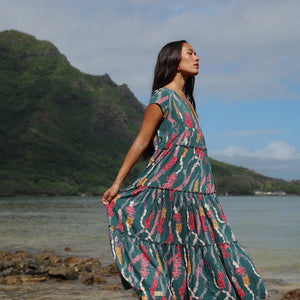 woman with brown hair wearing long tiered maxi dress in dark teal with shell lei print