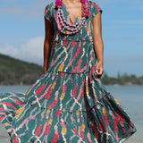 woman with brown hair wearing long tiered maxi dress in dark teal with shell lei print