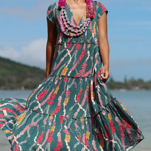 woman with brown hair wearing long tiered maxi dress in dark teal with shell lei print