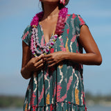 woman with brown hair wearing long tiered maxi dress in dark teal with shell lei print