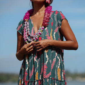 woman with brown hair wearing long tiered maxi dress in dark teal with shell lei print