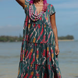 woman with brown hair wearing long tiered maxi dress in dark teal with shell lei print