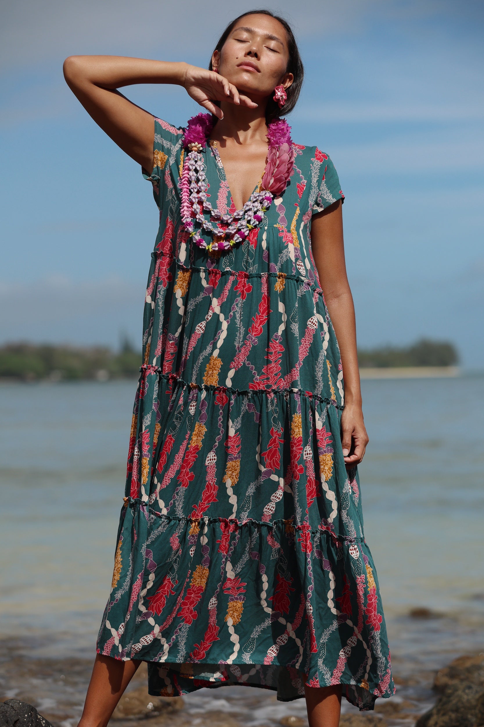 woman with brown hair wearing long tiered maxi dress in dark teal with shell lei print