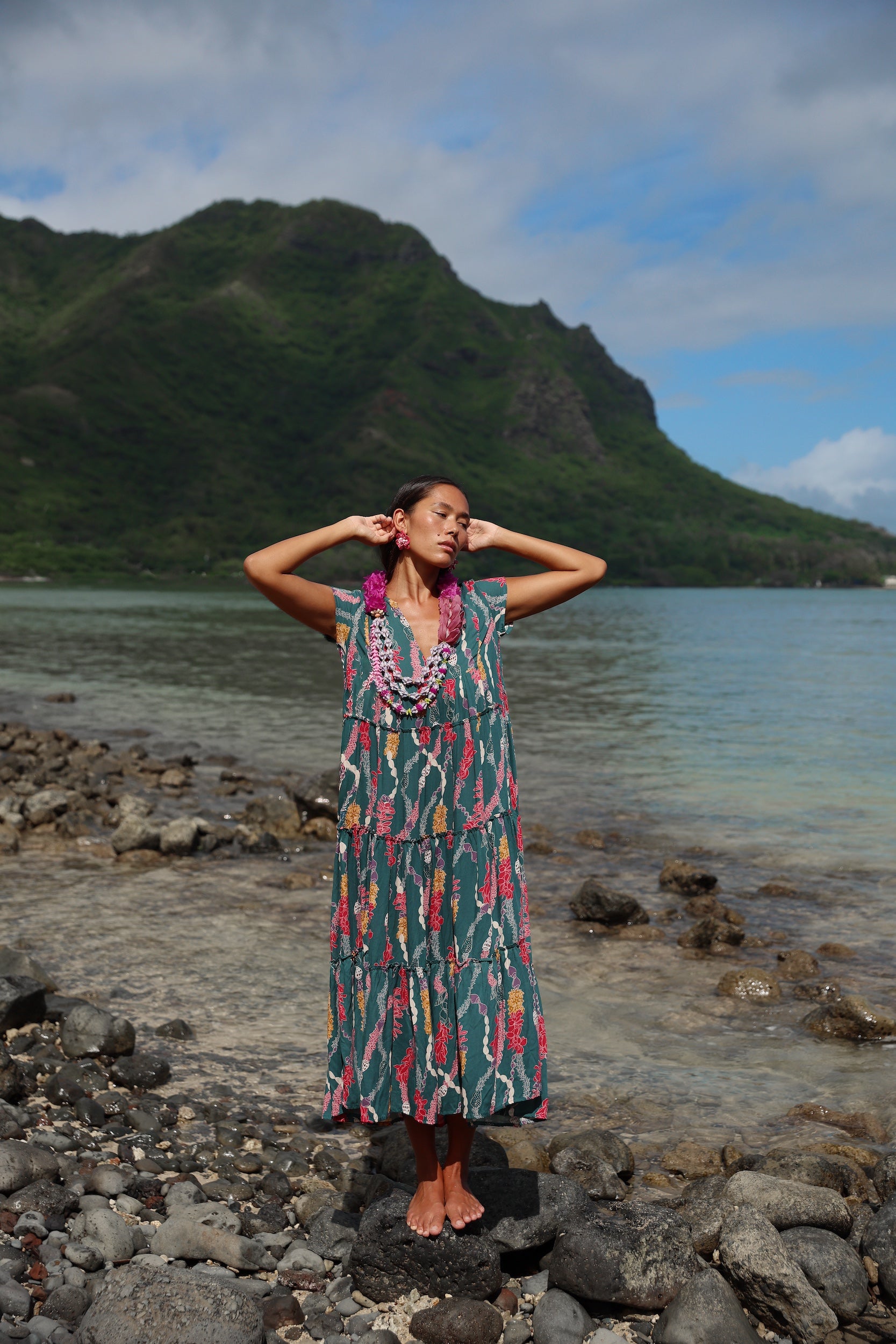 woman with brown hair wearing long tiered maxi dress in dark teal with shell lei print