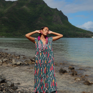 woman with brown hair wearing long tiered maxi dress in dark teal with shell lei print