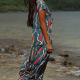woman with brown hair wearing long tiered maxi dress in dark teal with shell lei print