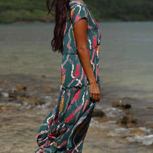 woman with brown hair wearing long tiered maxi dress in dark teal with shell lei print