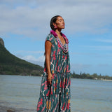 woman with brown hair wearing long tiered maxi dress in dark teal with shell lei print