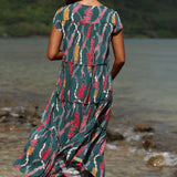 woman with brown hair wearing long tiered maxi dress in dark teal with shell lei print