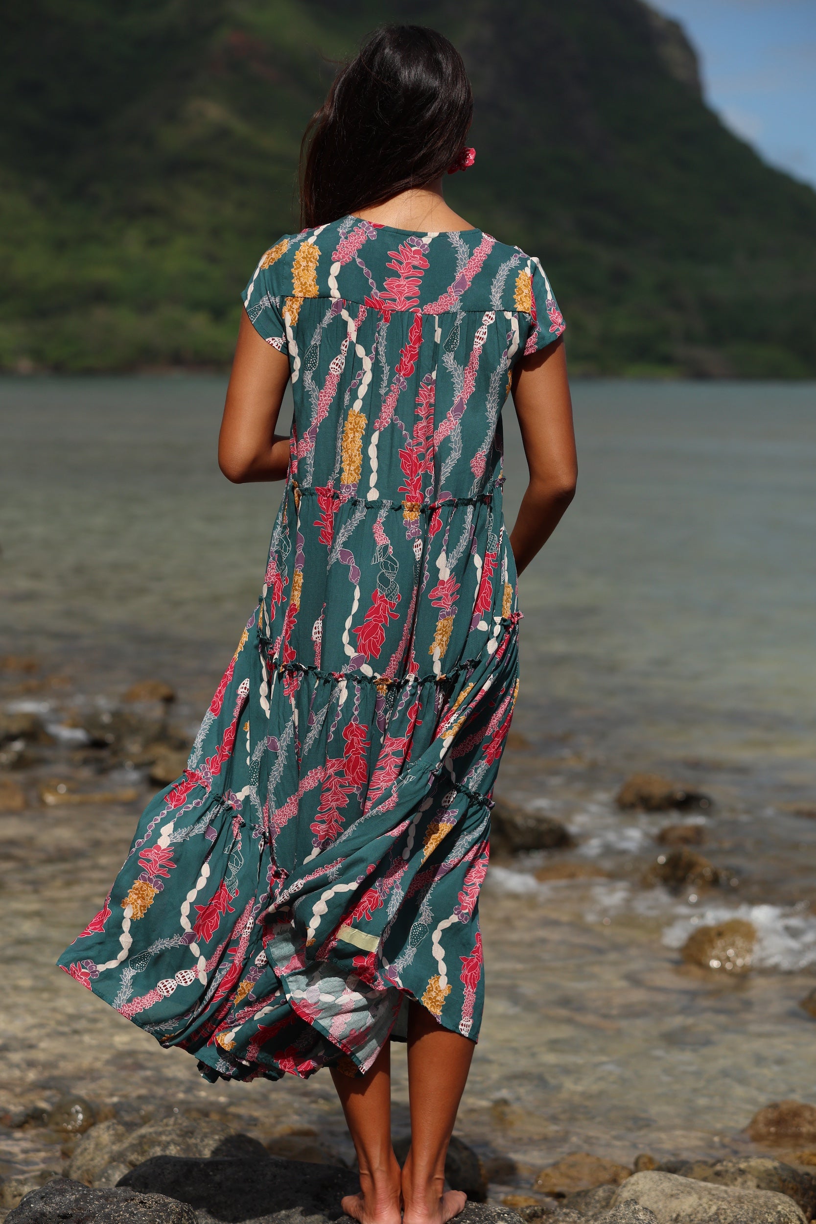woman with brown hair wearing long tiered maxi dress in dark teal with shell lei print