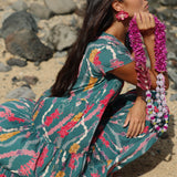 woman with brown hair wearing long tiered maxi dress in dark teal with shell lei print