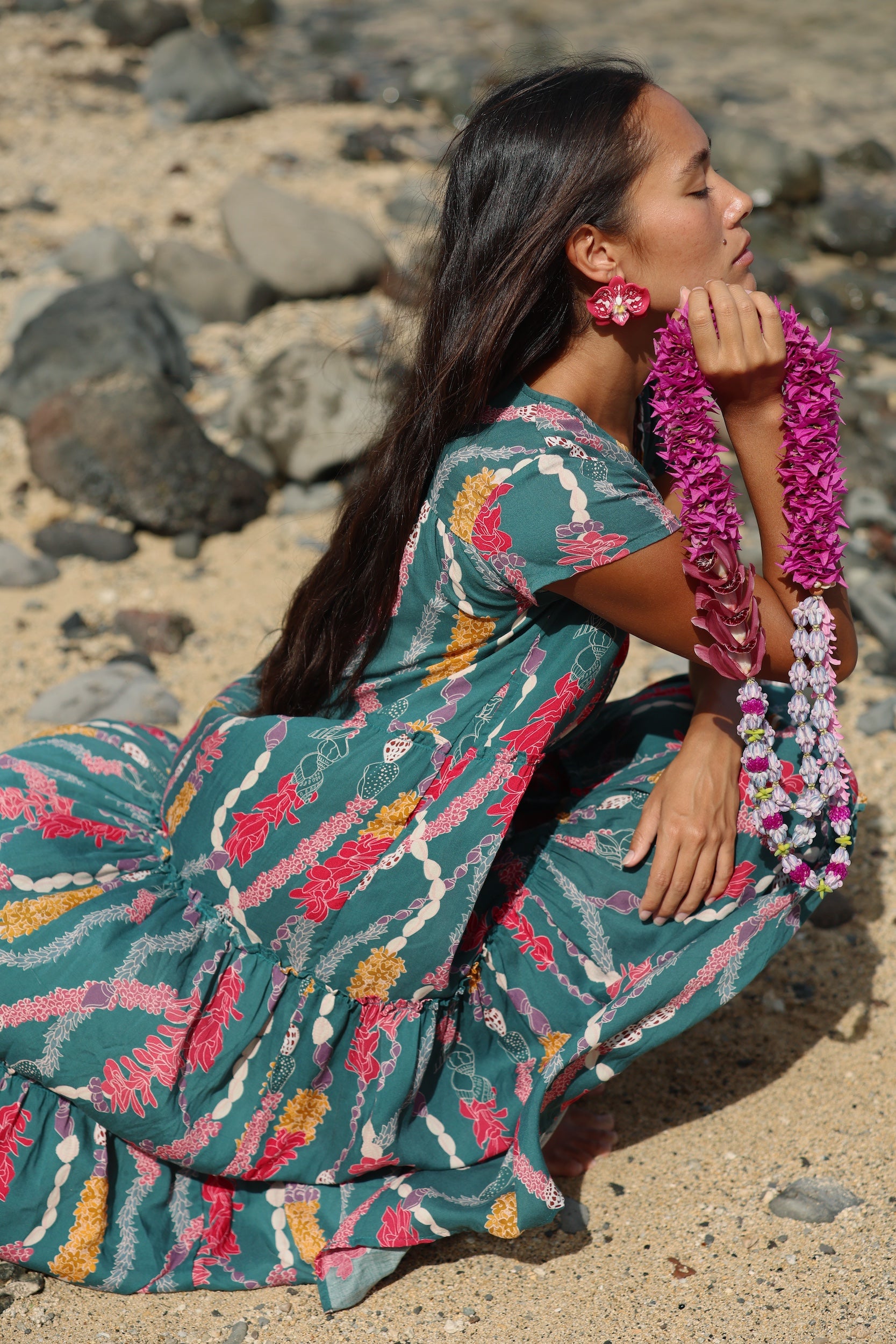 woman with brown hair wearing long tiered maxi dress in dark teal with shell lei print