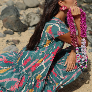 woman with brown hair wearing long tiered maxi dress in dark teal with shell lei print
