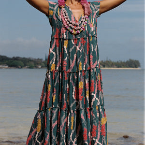 woman with brown hair wearing long tiered maxi dress in dark teal with shell lei print