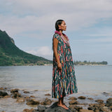 woman with brown hair wearing long tiered maxi dress in dark teal with shell lei print