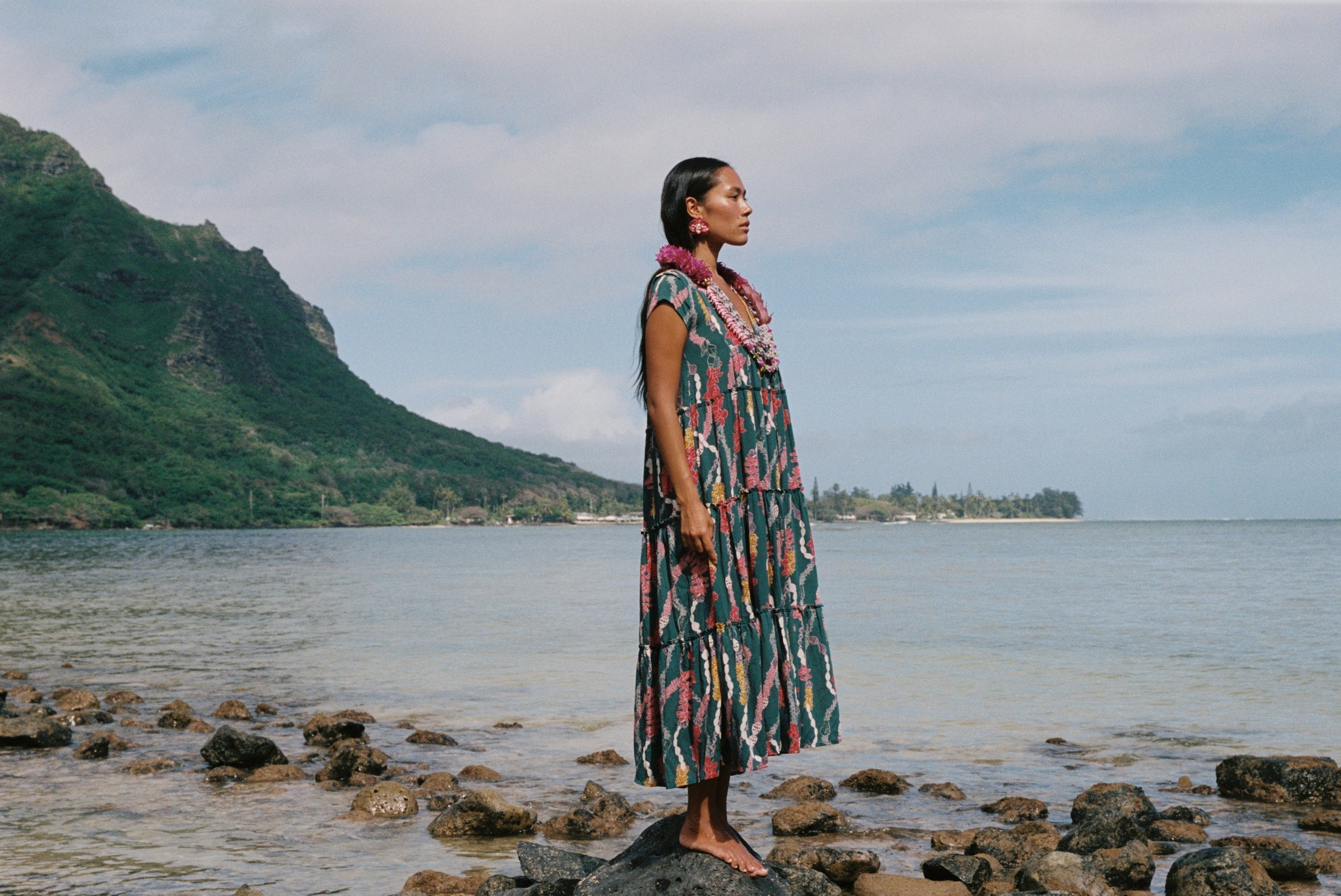 woman with brown hair wearing long tiered maxi dress in dark teal with shell lei print