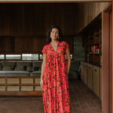 woman with brown hair wearing a flowy maxi tiered dress with retro pink pua print