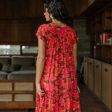 woman with brown hair wearing a flowy maxi tiered dress with retro pink pua print