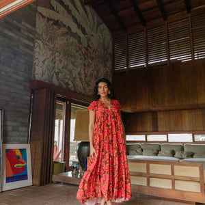 woman with brown hair wearing a flowy maxi tiered dress with retro pink pua print
