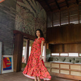 woman with brown hair wearing a flowy maxi tiered dress with retro pink pua print