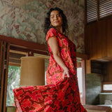 woman with brown hair wearing a flowy maxi tiered dress with retro pink pua print